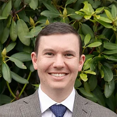 Dentist Jeff Miller Smiling In Front Of Shrub
